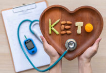 Keto Hype Backfires—Heart Risks Exposed Hands holding a heart-shaped wooden plate with keto food arranged to spell 'KETO'