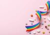 Colorful pills and a rainbow ribbon on a pink background