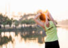 Low-Back Pain Breakthrough A woman stretching her arms by a lake during sunrise