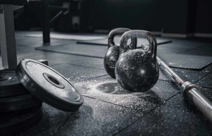 shutterstock_2034086534.jpg Kettlebells and weights on a gym floor with chalk dust