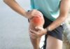 Simple Habits to Outsmart Osteoporosis Athlete holding their knee in pain while exercising outdoors