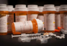 Various prescription medication bottles and syringes on a table