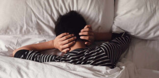 Child lying in bed with hands over ears