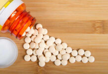 Spilled white pills from a prescription bottle on a wooden surface