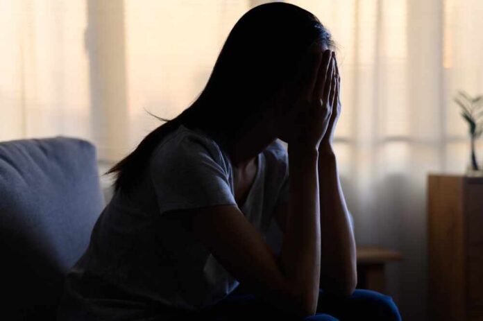 shutterstock_2140657535.jpg A silhouette of a person sitting with their head in their hands, conveying distress