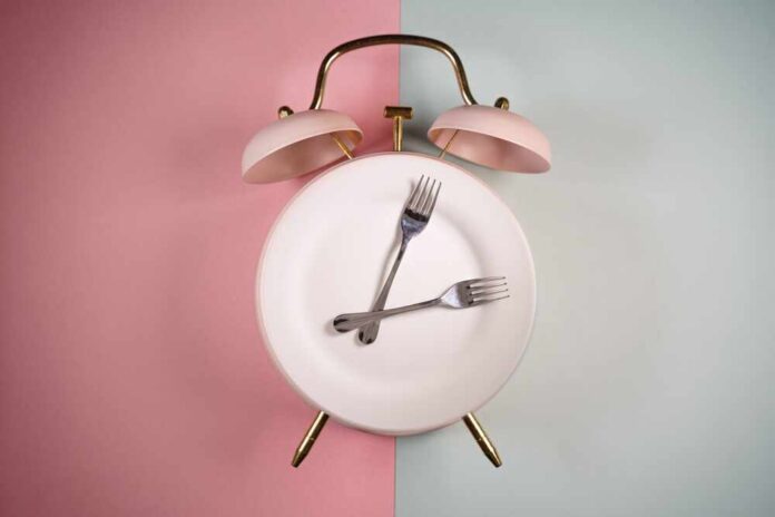 shutterstock_2254994603.jpg An alarm clock with a plate and two forks arranged in a creative design