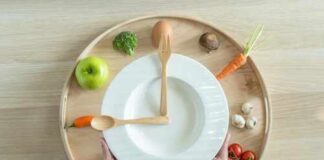 Hands holding a white plate surrounded by fresh vegetables and an egg