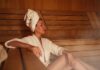 Woman relaxing in a sauna wearing a robe and towel