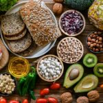 A variety of fresh foods including vegetables, fruits, grains, and proteins arranged on a wooden surface