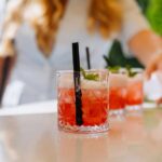 Close-up of cocktails on a table with a person reaching for one