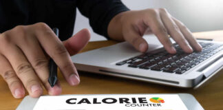 Person using a calorie counter app on a tablet while working on a laptop