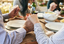 Couple holding hands over a dining table with food and drinks