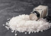 A glass salt shaker tipped over with salt spilling out