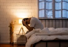 Scientists Reveal Fast Stress-Relieving Hack A person sitting on a bed with their head in their hands, expressing distress