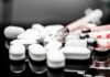 White pills and syringes arranged on a reflective surface