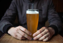 Moderate Drinking’s Alarming Brain Impact Person holding a glass of craft beer in a bar