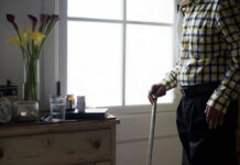 How Indoor Life Quietly Wrecks Your Biology Elderly man standing with a cane next to a table with flowers and medication