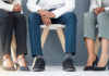 Three individuals in business attire sitting on chairs, showcasing their shoes and legs