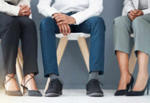 Three individuals in business attire sitting on chairs, showcasing their shoes and legs