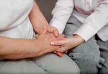 Silent Epidemic That’s Crippling Middle Age Americans An older persons hand being held by a younger persons hand, symbolizing care and connection