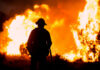 Human Spark Ignites America’s Biggest Wildfire Silhouette of a firefighter standing in front of a large wildfire