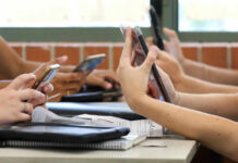 Students in a classroom using smartphones for a group activity