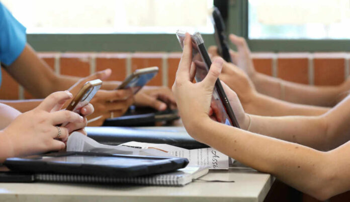 Students in a classroom using smartphones for a group activity