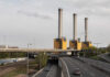 The City Pollutant Quietly Clogging Your Arteries Industrial power plant with three tall smokestacks beside a highway