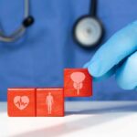Kidney Disease Breakthrough Stuns Doctors A doctor's gloved hand placing red blocks with health symbols on a table