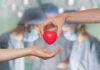 Closed-Chest Heart Fix Stuns Surgeons Two hands exchanging a red heart symbol in a surgical setting