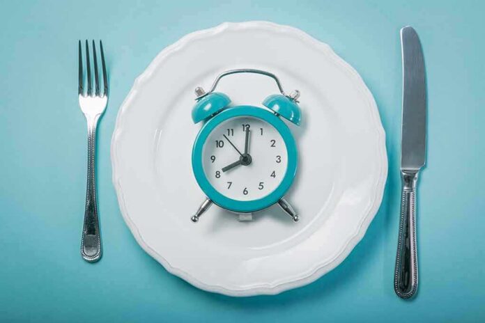 shutterstock_1036153894 Alarm clock on a white plate with fork and knife