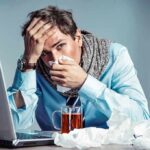 Sick man at desk blowing his nose