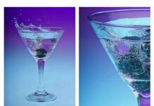 Martini glass with blackberries splashing into sparkling water