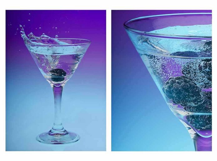 Martini glass with blackberries splashing into sparkling water