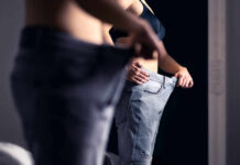 Person trying on oversized pants in front of a mirror