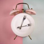 An alarm clock with a plate and two forks arranged in a creative design