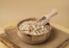 A wooden bowl filled with oats and a wooden scoop
