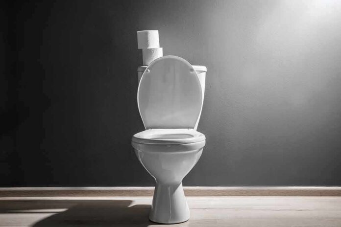 White toilet with open lid against gray wall
