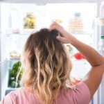 Person looking into an open refrigerator