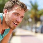 man in athletic tank top resting outdoors