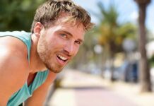 man in athletic tank top resting outdoors