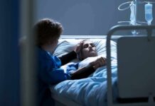 New Paperwork Unmasks America’s Riskiest Cancer Group Patient in hospital bed with visitor holding their hand