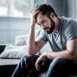 Man sitting on a couch with head in hand
