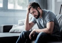 Man sitting on a couch with head in hand