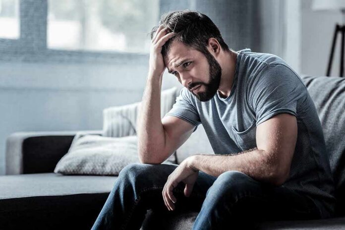 Man sitting on a couch with head in hand