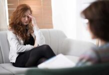 Woman with hand on forehead sitting on couch during therapy session