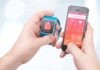 hands holding a smartwatch and a smartphone with health app