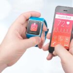 hands holding a smartwatch and a smartphone with health app