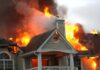 House engulfed in flames with heavy smoke from the roof