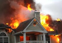 House engulfed in flames with heavy smoke from the roof